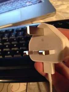 Hand holding a three-pin plug as used in Tanzania