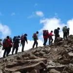 Silhouettes of line of trekkers and porters on Kilimanjaro in desert zone